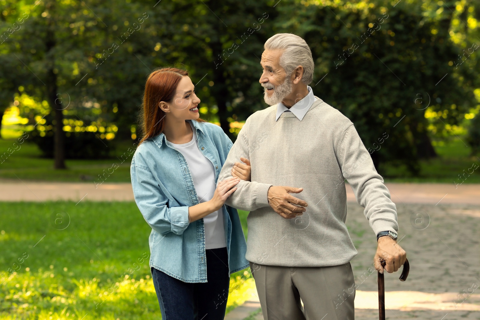 Photo of Senior man with walking cane and young woman in park