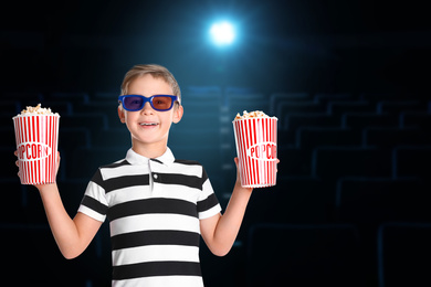 Cute boy in 3D glasses with popcorn buckets in cinema, space for text