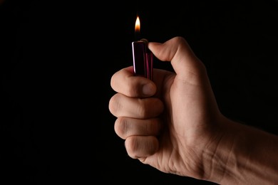 Photo of Man holding lighter on black background, closeup. Space for text