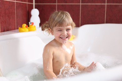 Happy girl having fun in bathtub at home