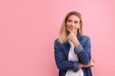 Photo of Portrait of smiling middle aged woman with blonde hair on pink background. Space for text