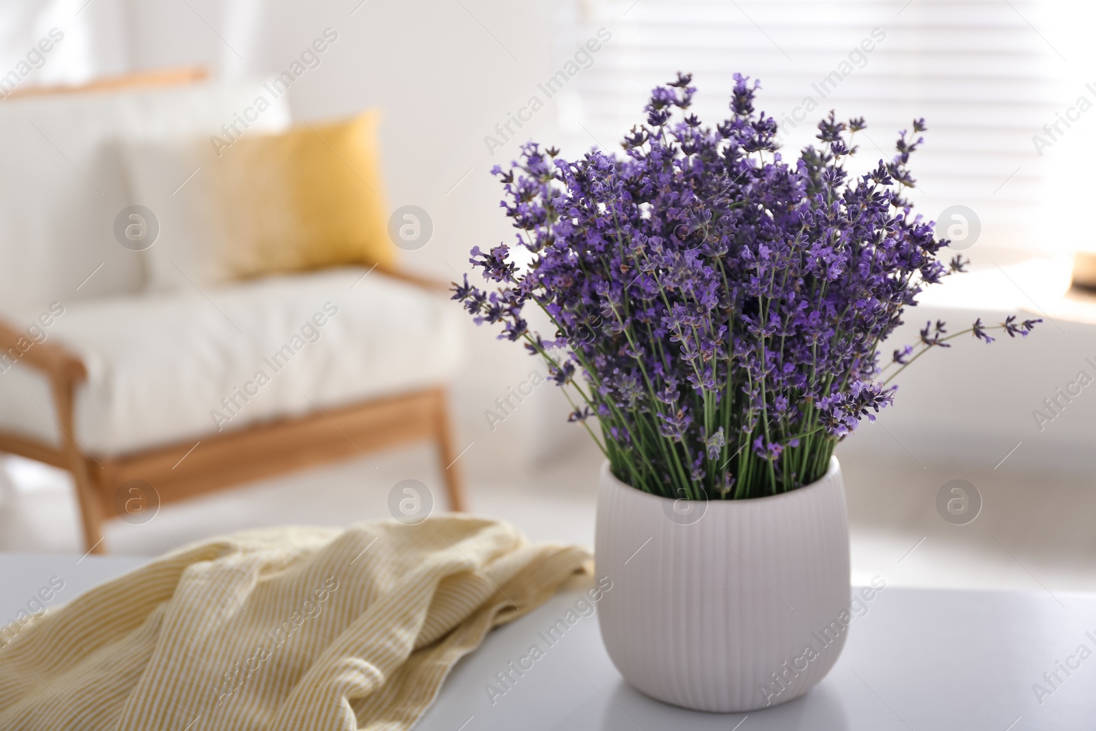 Photo of Beautiful lavender flowers and yellow shirt on white table indoors. Space for text