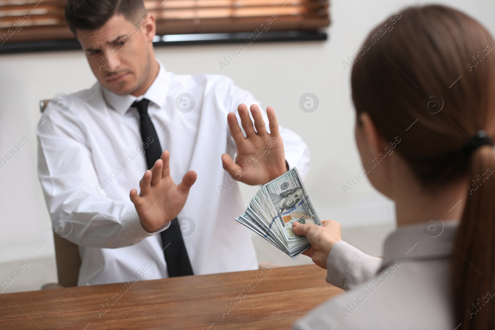 Photo of Man refusing to take bribe at table indoors