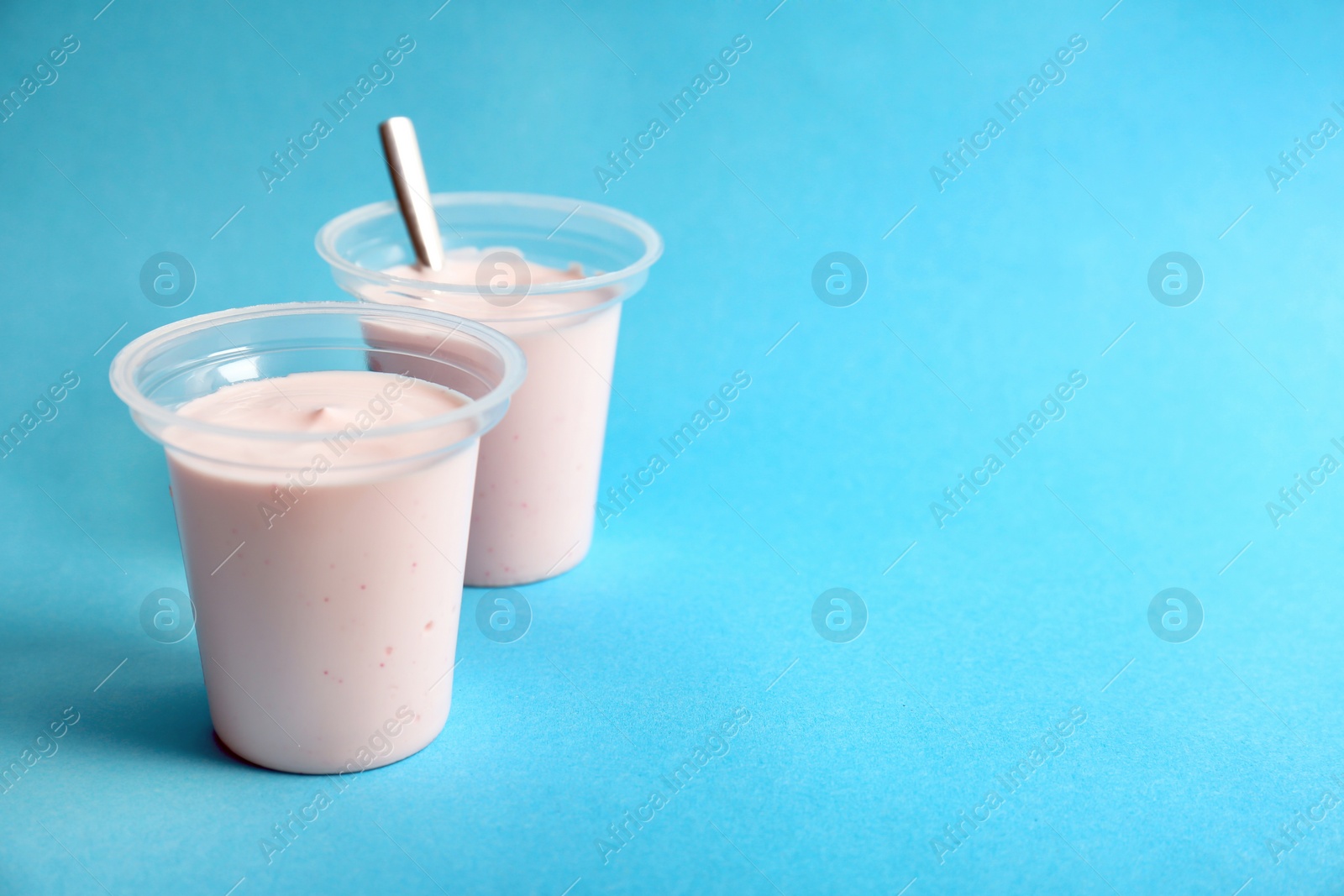 Photo of Plastic cups with tasty yogurt on color background