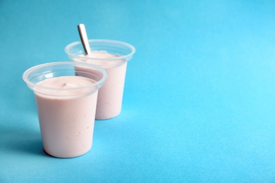 Plastic cups with tasty yogurt on color background