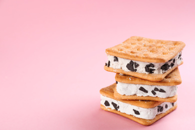 Photo of Sweet delicious ice cream cookie sandwiches on pink background. Space for text