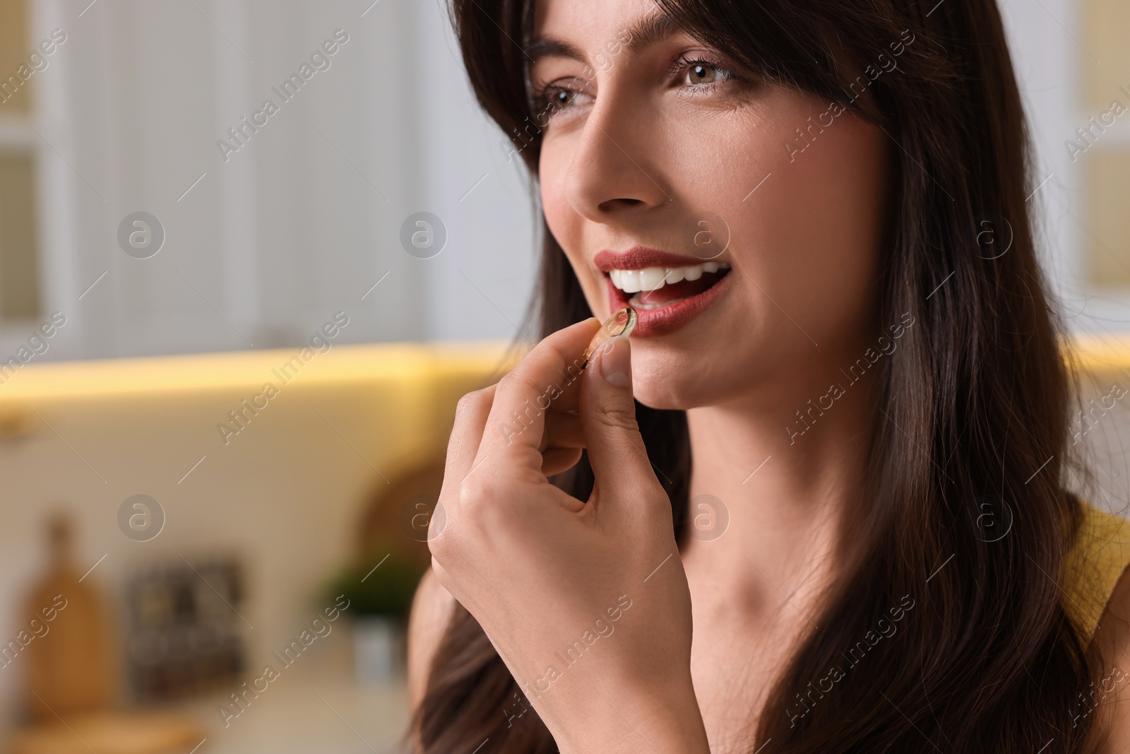 Photo of Beautiful woman taking vitamin pill at home, space for text