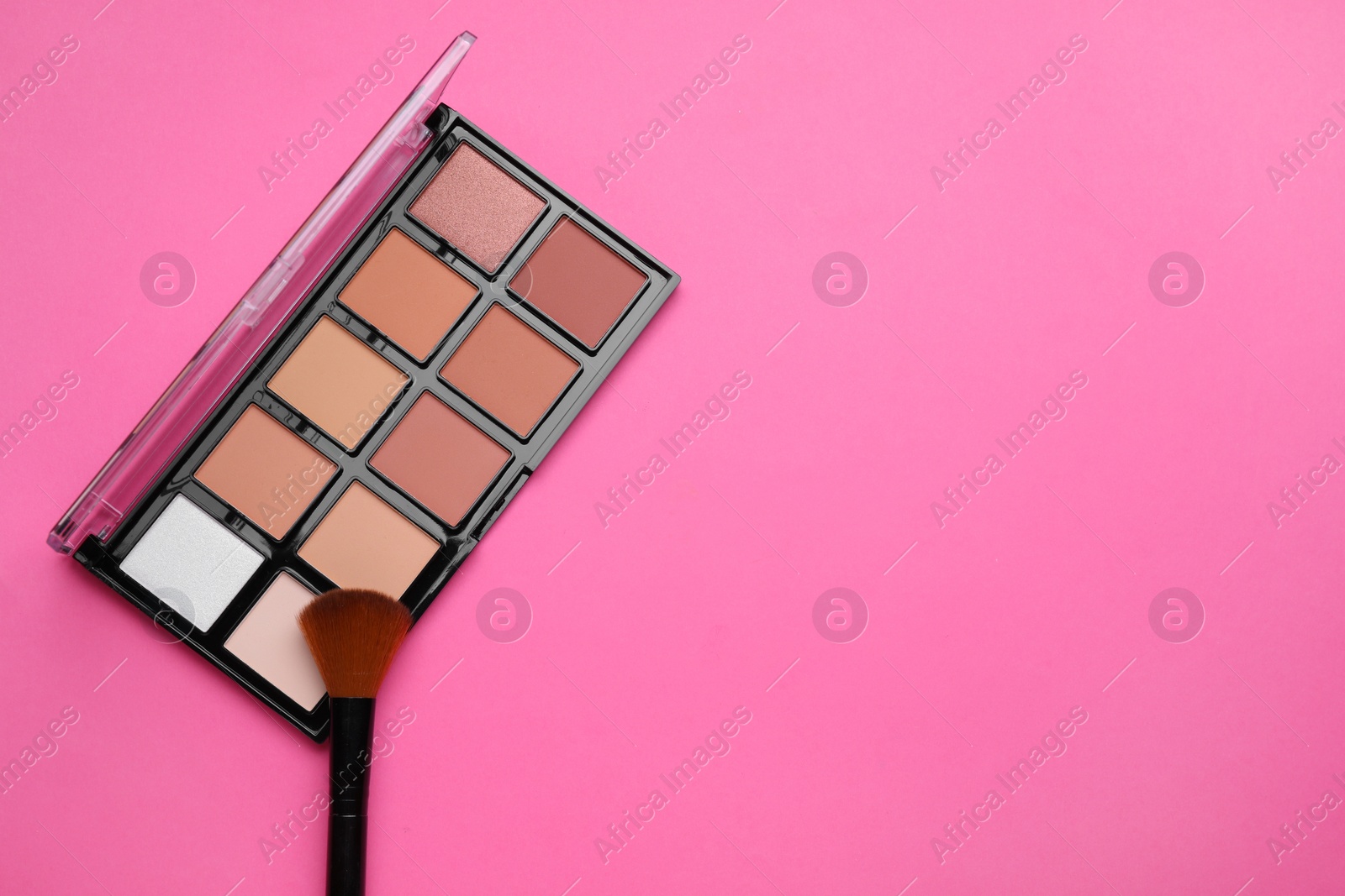 Photo of Colorful contouring palette and brush on pink background, top view with space for text. Professional cosmetic product