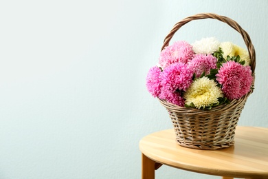 Photo of Basket with beautiful asters on table, space for text. Autumn flowers