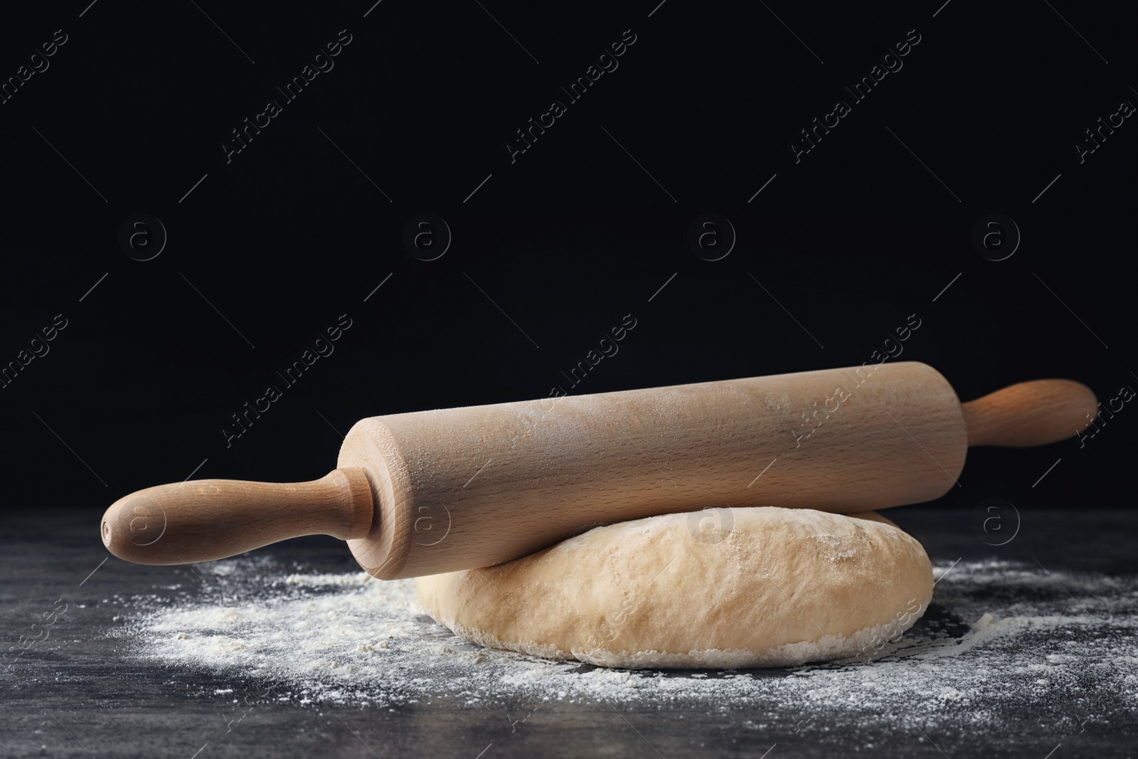 Photo of Raw wheat dough with flour and rolling pin on table