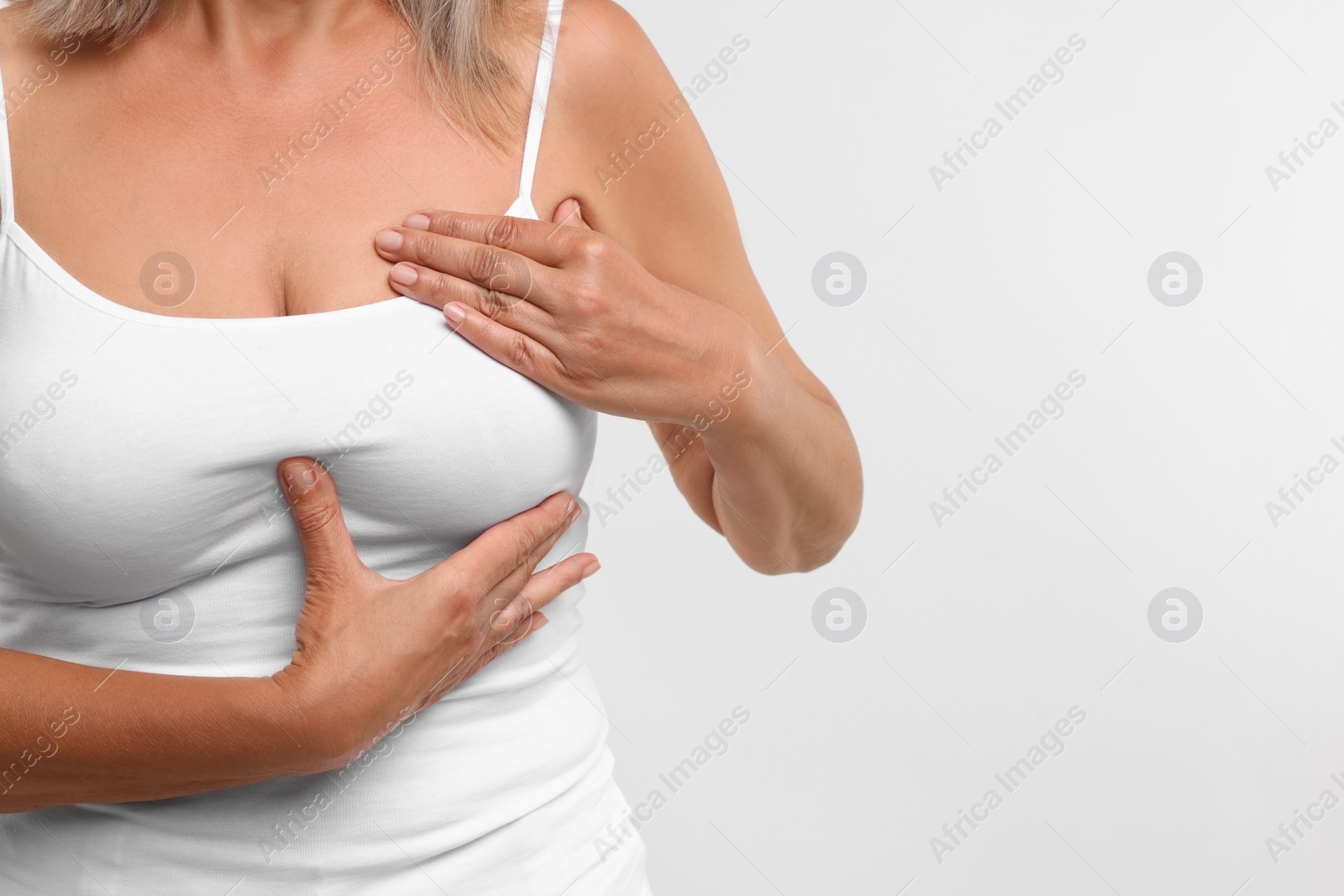 Photo of Woman doing breast self-examination on white background, closeup. Space for text