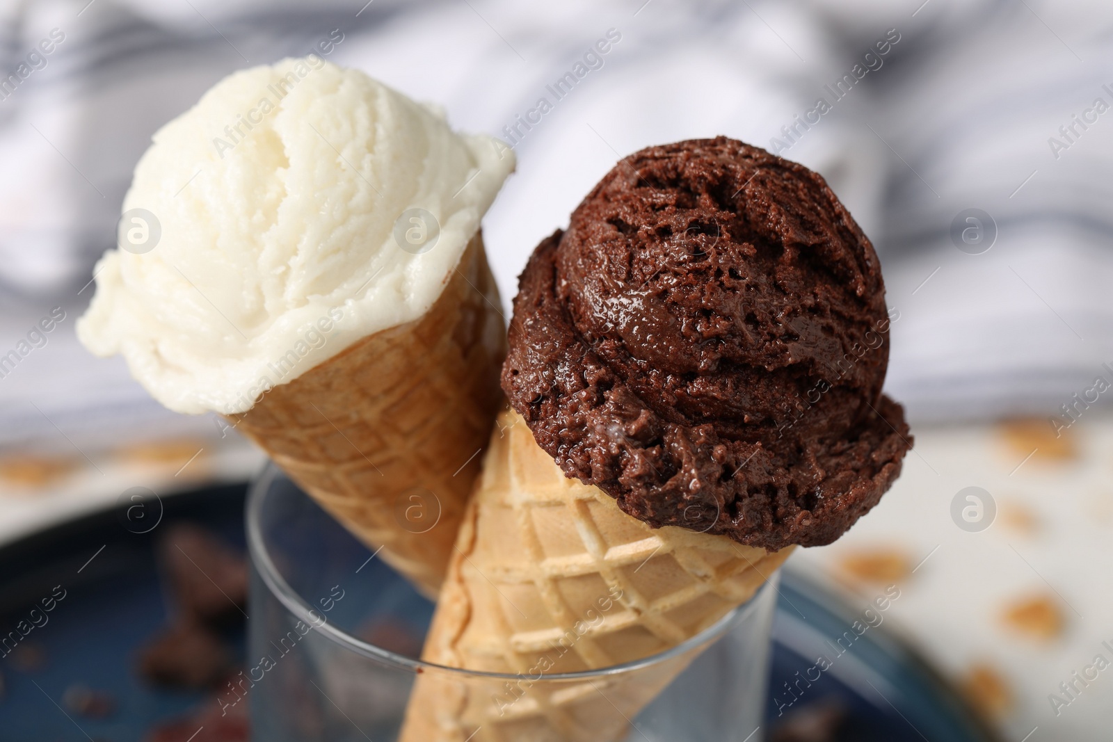 Photo of Tasty ice cream scoops in waffle cones on blurred background, closeup