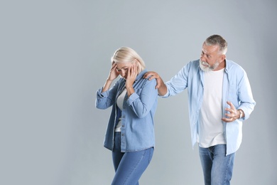 Photo of Mature couple having argument on grey background. Relationship problems