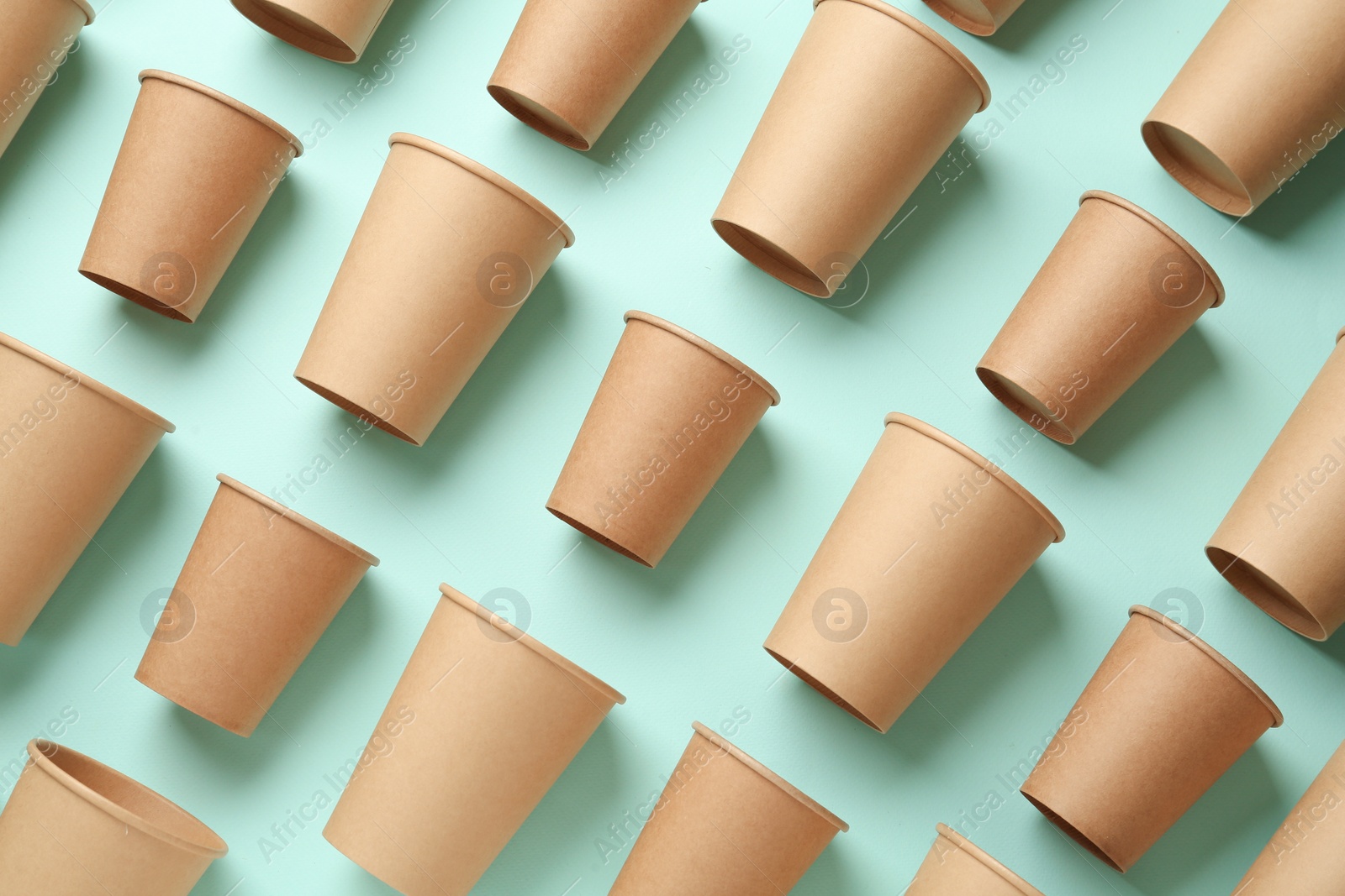 Photo of Disposable eco friendly cups on light blue background, flat lay