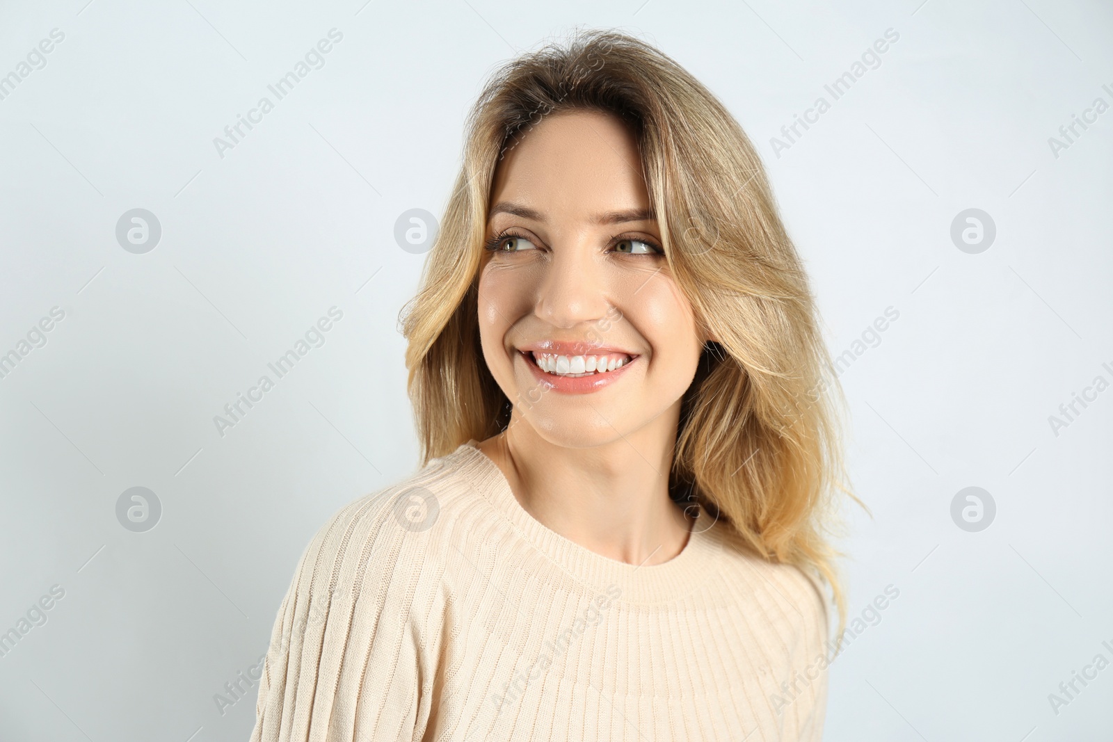 Photo of Portrait of happy young woman with beautiful blonde hair and charming smile on light background