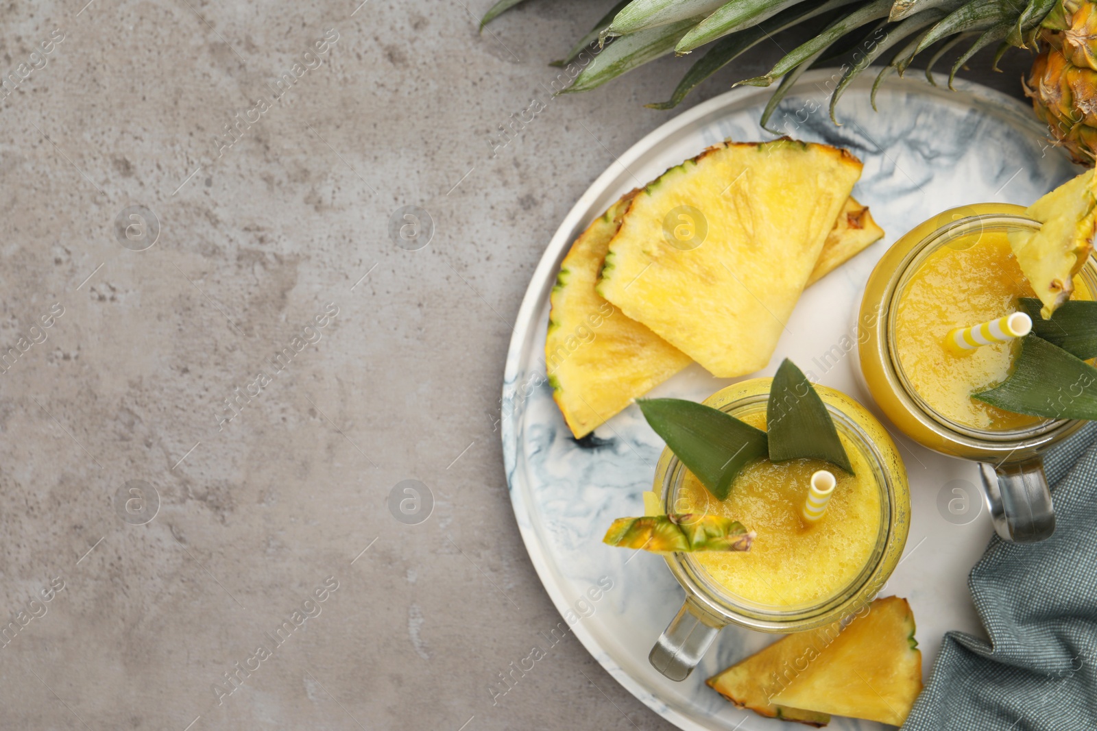 Photo of Tray with tasty pineapple smoothie and sliced fruit on grey table, flat lay. Space for text