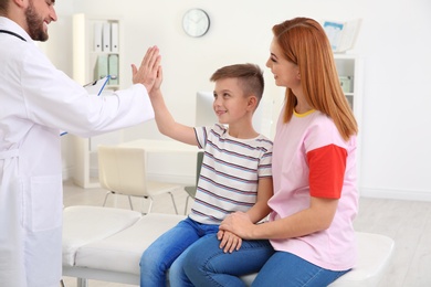 Children's doctor giving high five to patient in hospital