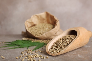 Photo of Scoop with hemp seeds on table, closeup