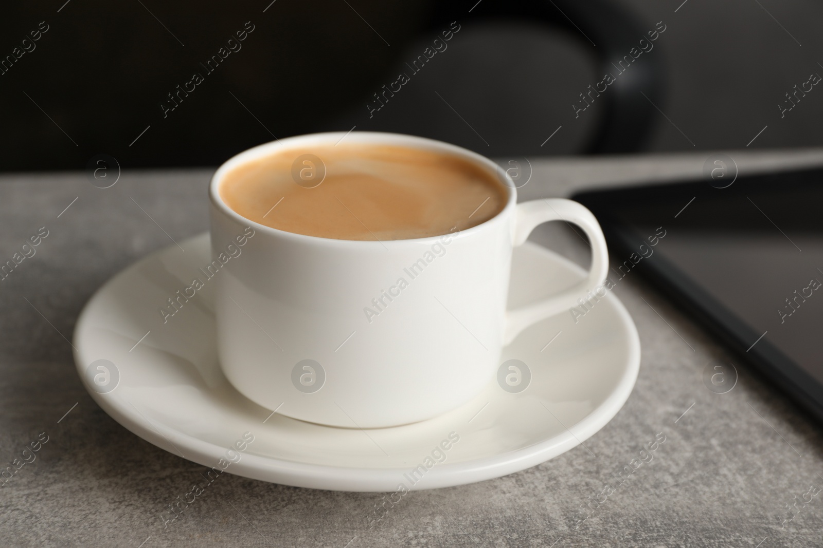 Photo of Coffee Break at workplace. Cup of hot drink on grey table