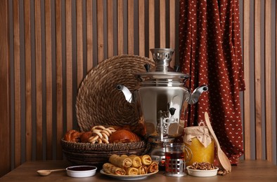Photo of Traditional Russian samovar with treats on wooden table