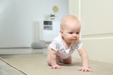 Cute little baby crawling on carpet indoors