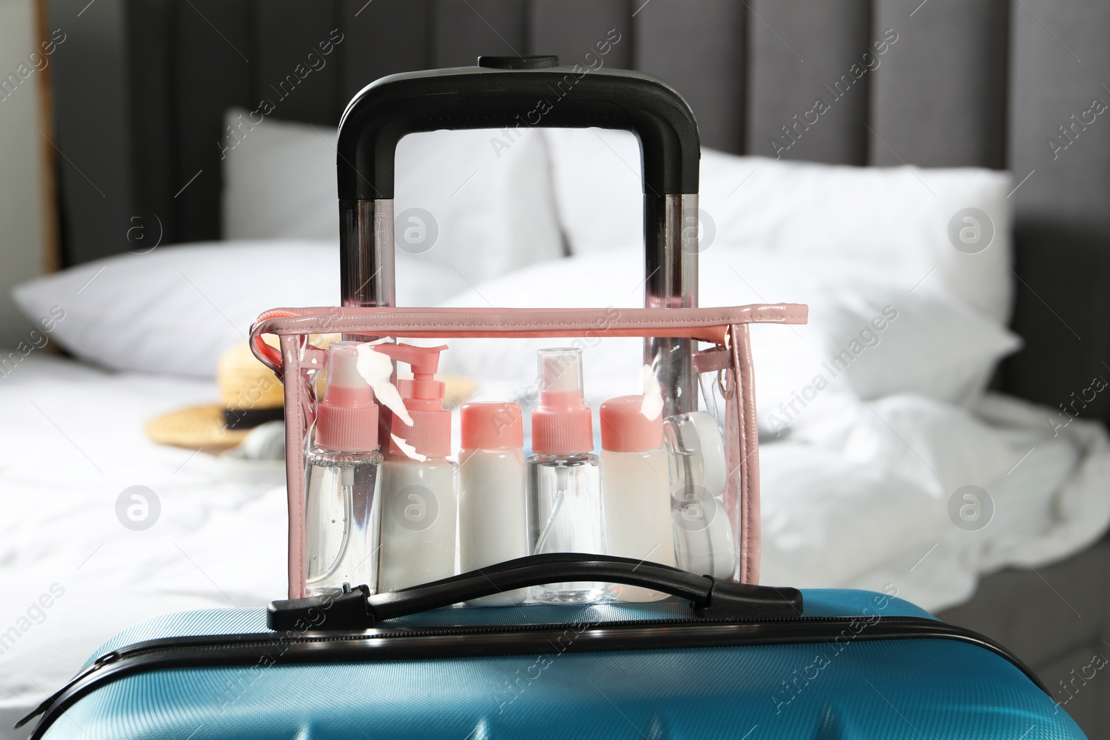 Photo of Cosmetic travel kit. Plastic bag with small containers of personal care products on suitcase in bedroom