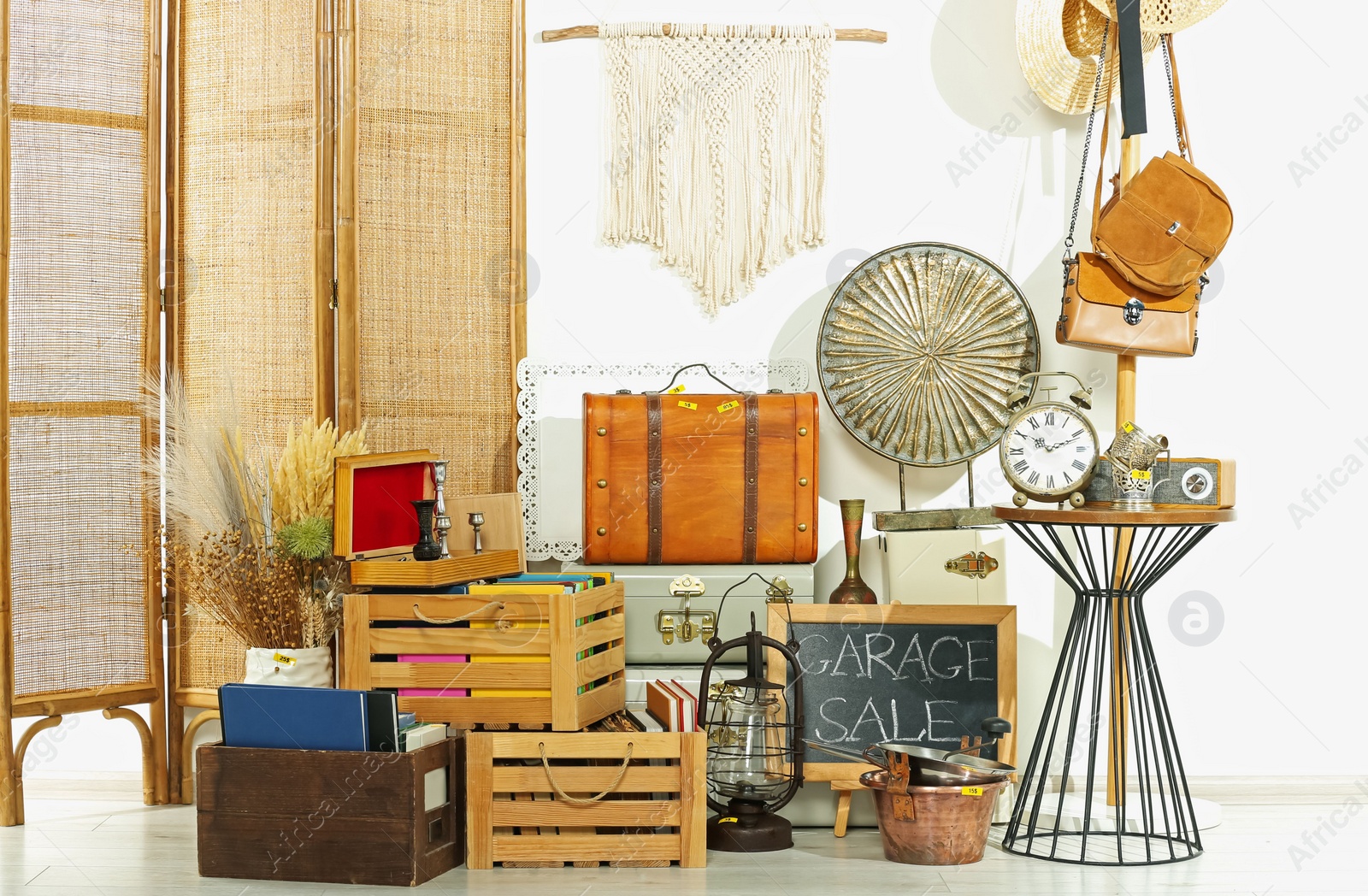 Photo of Sign Garage Sale written on blackboard near many different stuff indoors