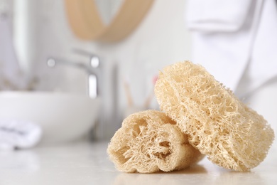 Photo of Natural loofah sponges on table in bathroom, closeup. Space for text