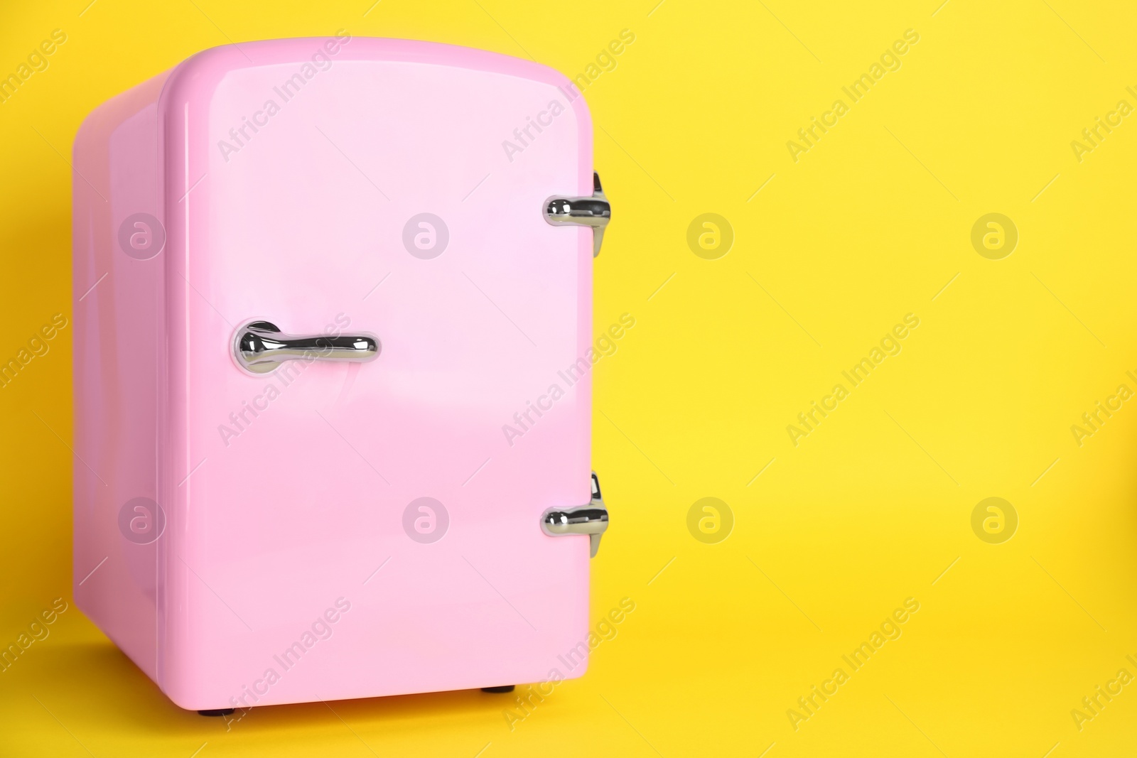 Photo of Cosmetic refrigerator on yellow background, space for text