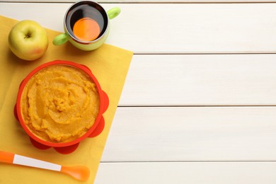 Photo of Plastic dishware with healthy baby food on white wooden table, flat lay. Space for text