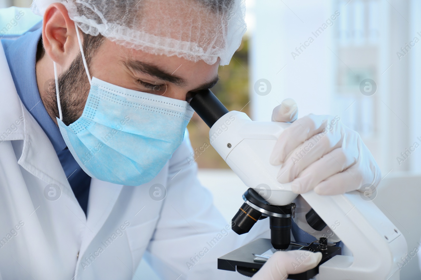 Photo of Young scientist working with microscope in laboratory, closeup. Chemical analysis