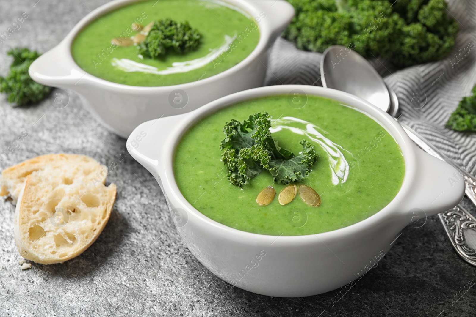 Photo of Tasty kale soup with pumpkin seeds on grey table