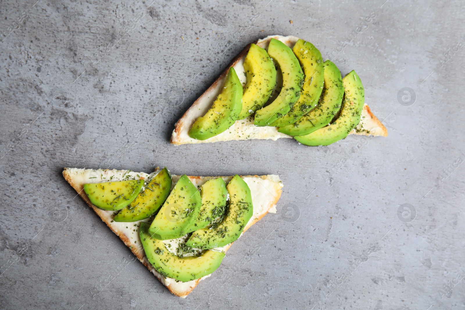 Photo of Tasty toasts with avocado on light grey table, flat lay