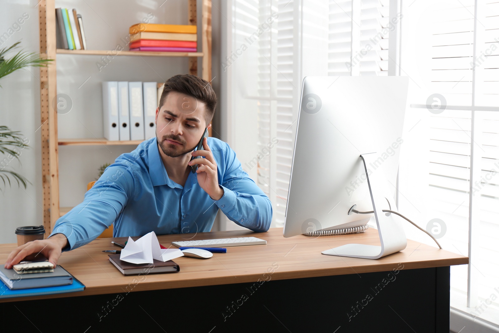 Photo of Lazy employee talking on smartphone at table in office