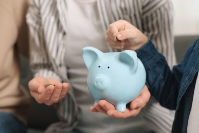 Photo of Family budget. Little boy and his parents putting coin into piggy bank, closeup