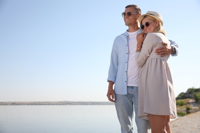 Happy couple walking along waterfront on summer day