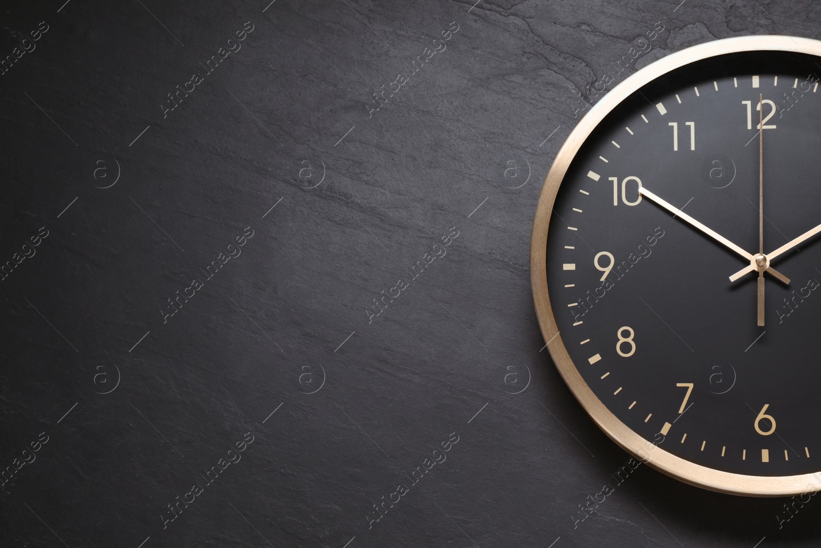 Photo of Stylish round clock on black table, top view with space for text. Interior element