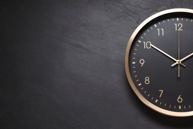 Stylish round clock on black table, top view with space for text. Interior element