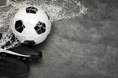 Sports equipment. Soccer ball, net and sneakers on grey textured table, flat lay. Space for text