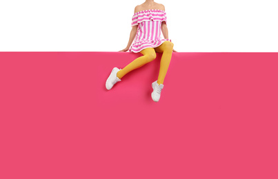 Photo of Woman wearing yellow tights and stylish shoes sitting on color background, closeup