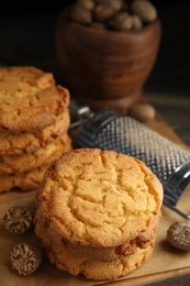 Photo of Tasty cookies, nutmeg seeds and grater on wooden board