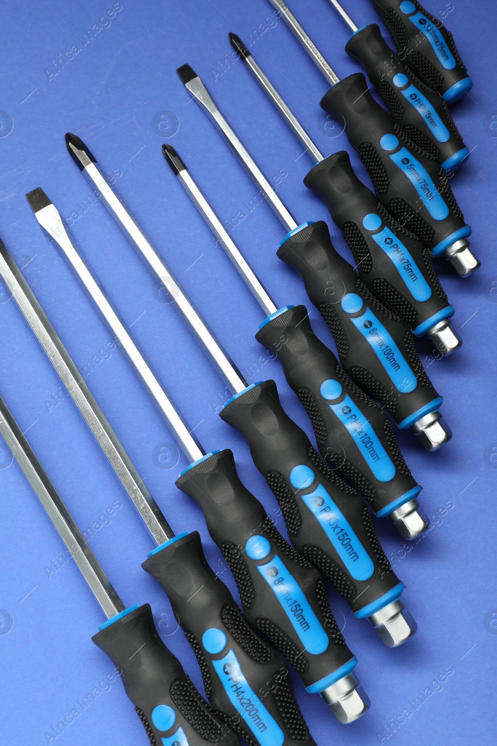 Photo of Set of screwdrivers on blue background, flat lay