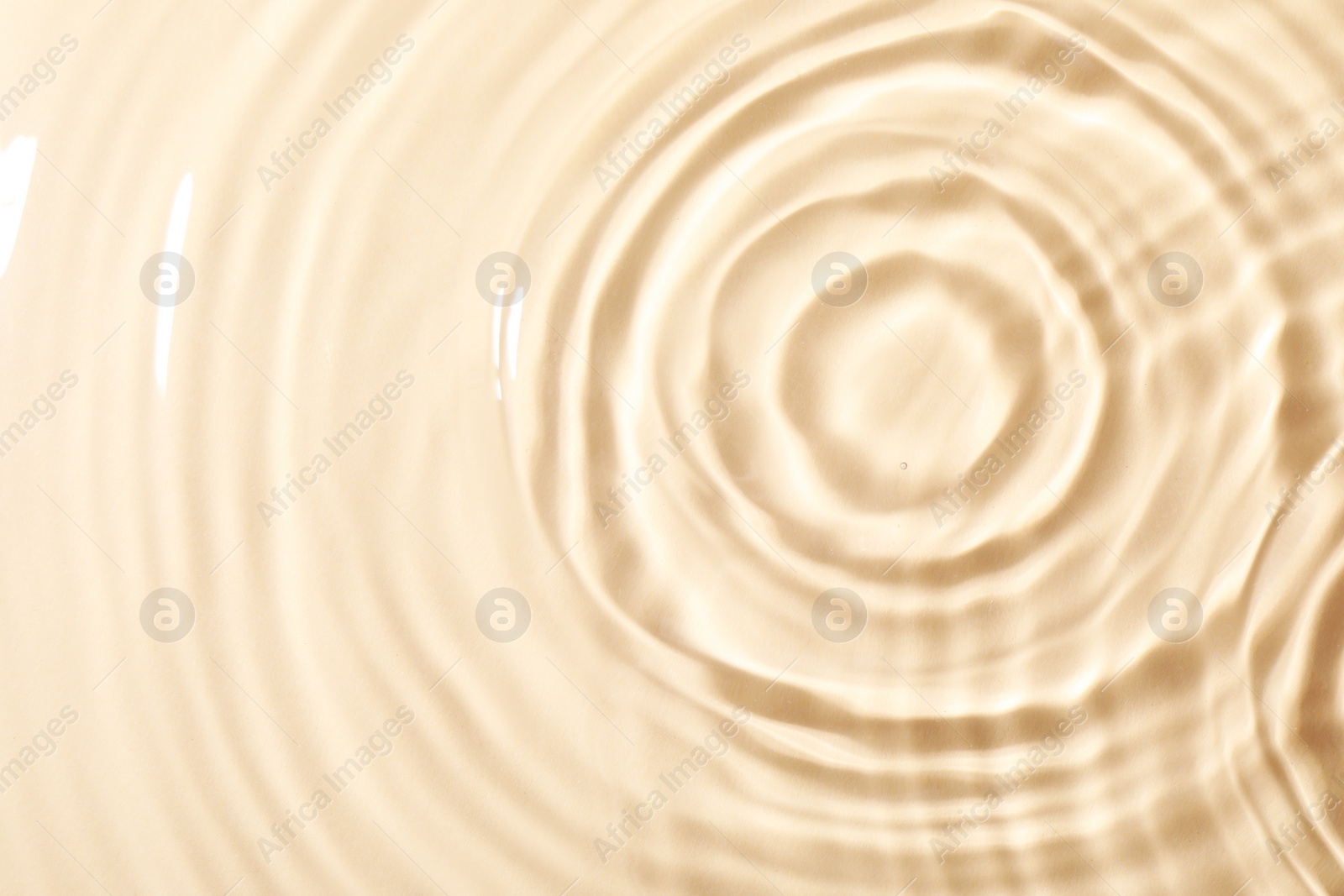 Photo of Closeup view of water with rippled surface on beige background