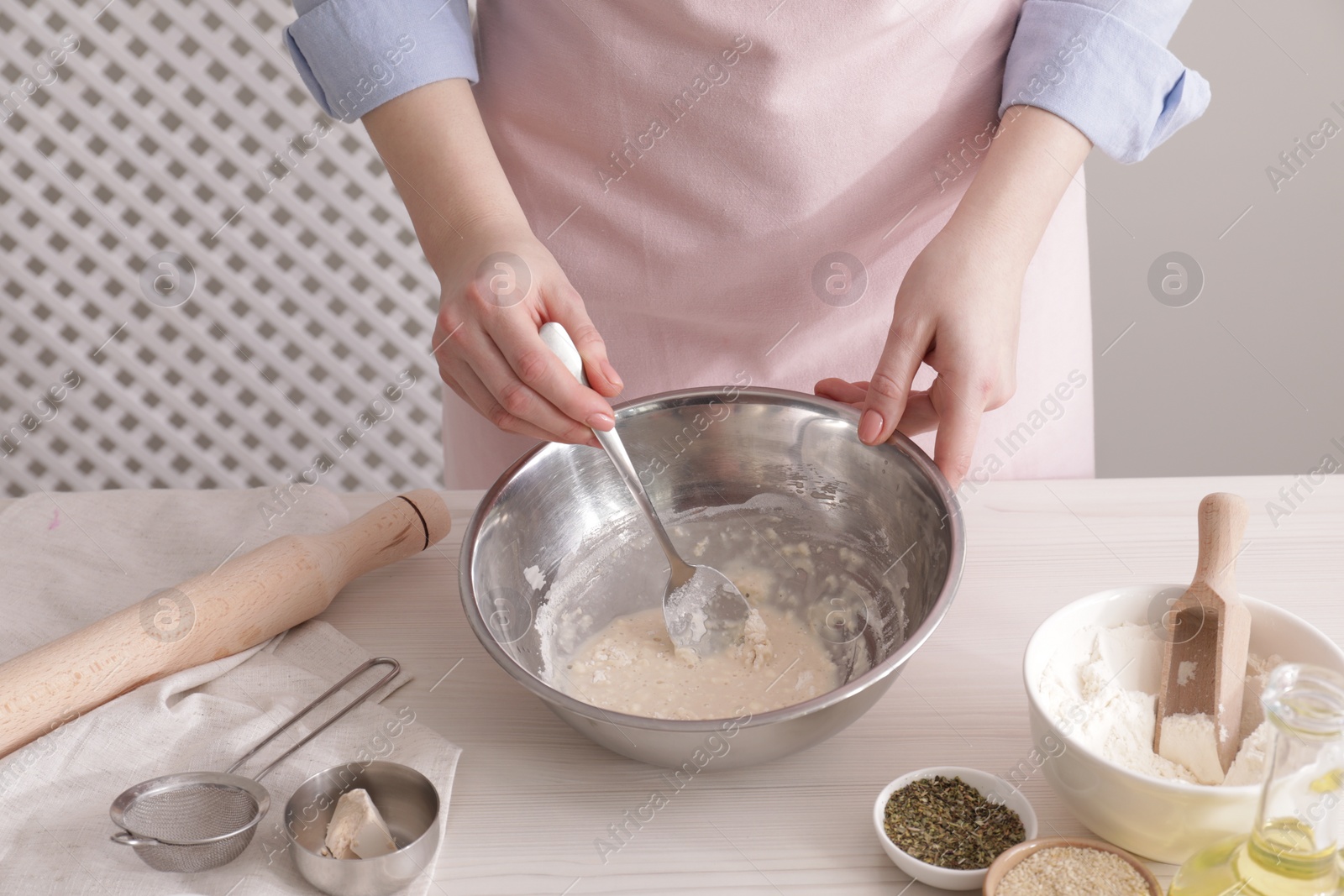 Photo of Woman making traditional grissini at white wooden table indoors, closeup