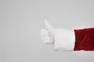 Photo of Santa Claus showing thumb up on light grey background, closeup of hand