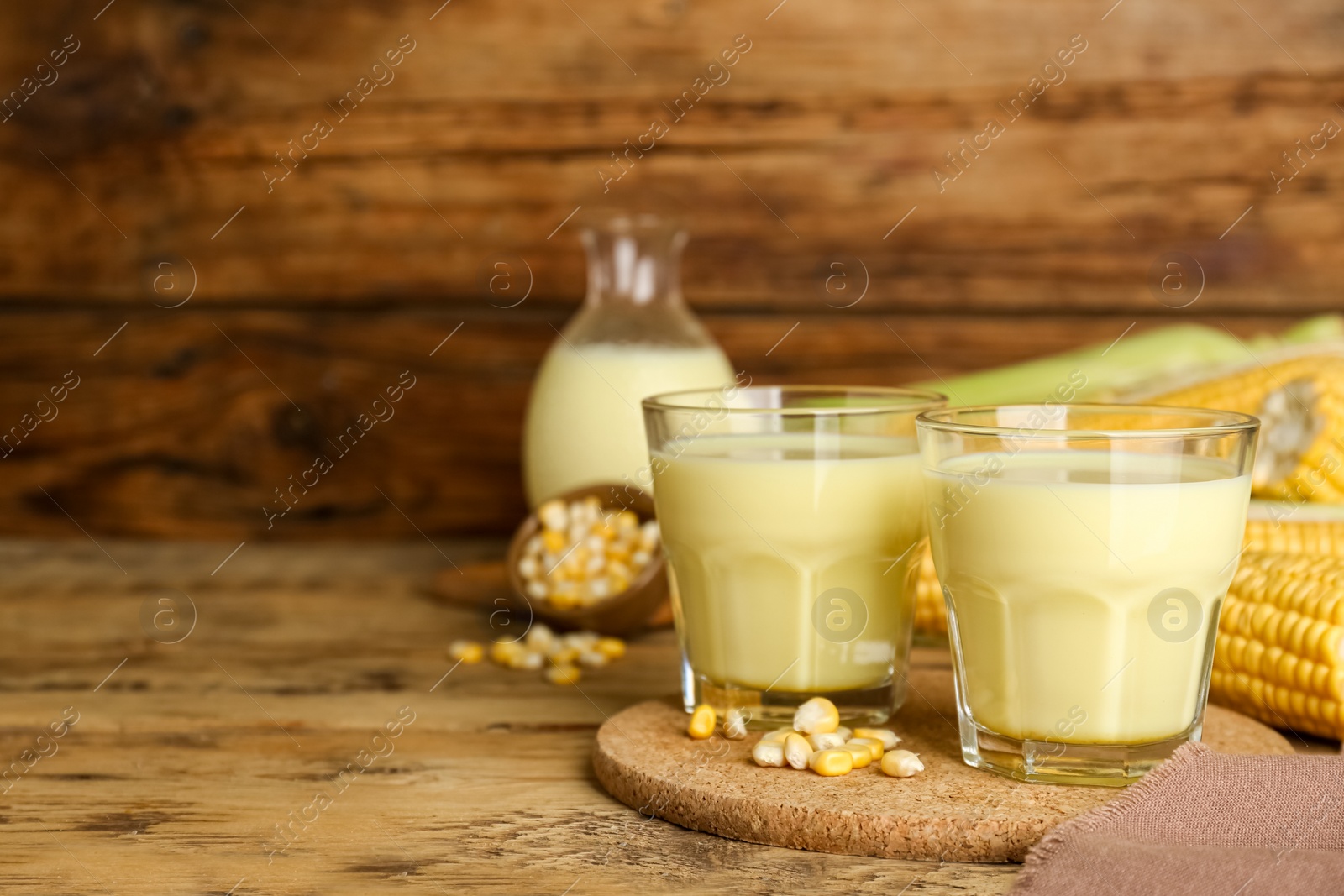 Photo of Tasty fresh corn milk in glasses on wooden table. Space for text