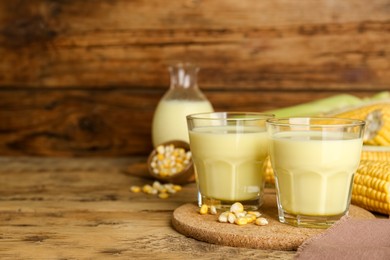 Tasty fresh corn milk in glasses on wooden table. Space for text