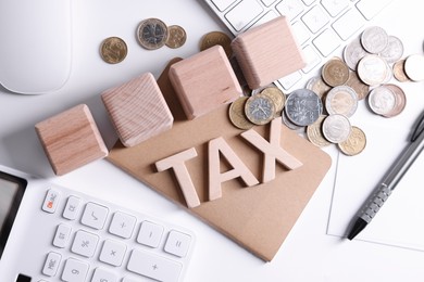 Photo of Word Tax, wooden cubes, calculator, coins, keyboard and pen on white table