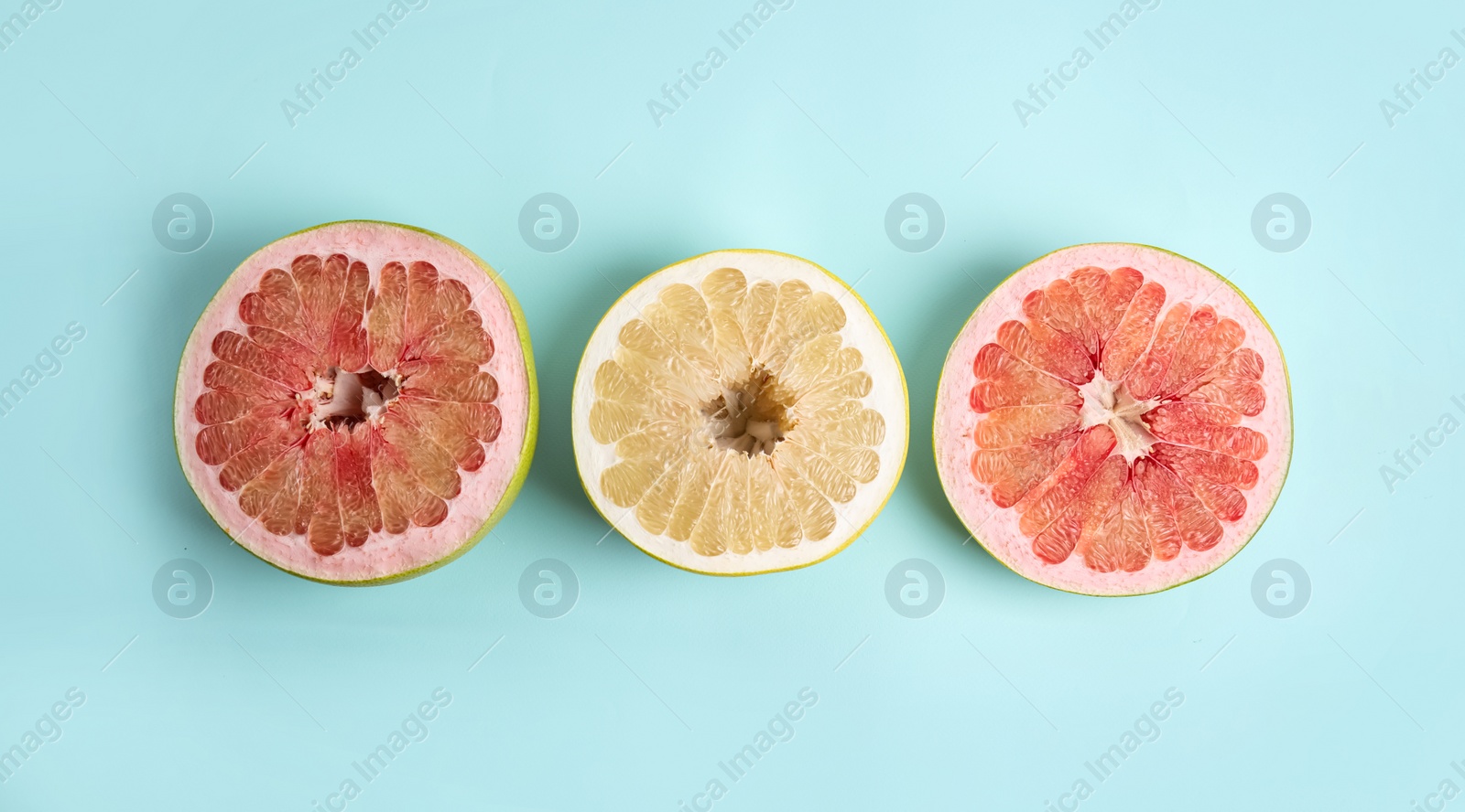 Photo of Fresh cut pomelo fruits on light blue background, flat lay