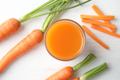 Photo of Glass with carrot juice and fresh vegetable on table, top view